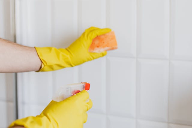 person using a sponge and spray bottle to clean